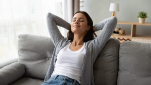 Woman breathing with eyes closed, leaning back on a couch.