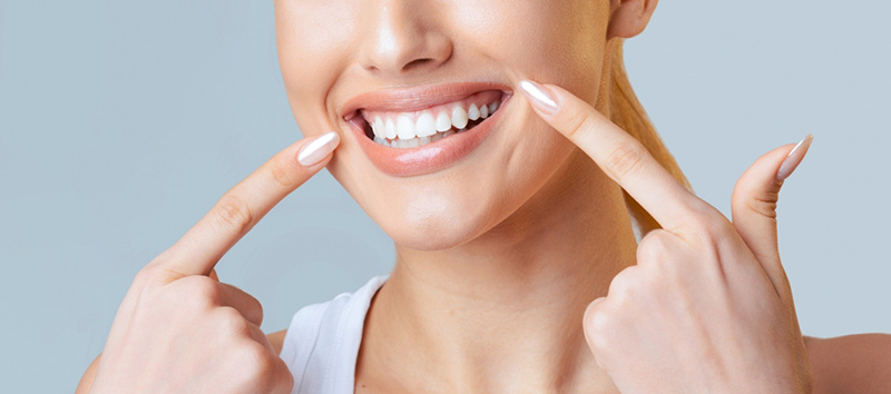 Woman points to her newly whitened teeth