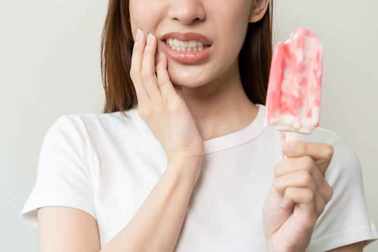 Woman experiencing tooth sensitivity from an ice cream