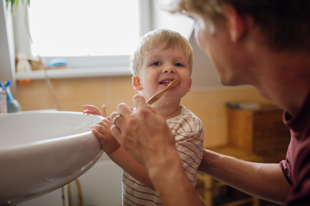 Father brushes his young boy’s teeth with him