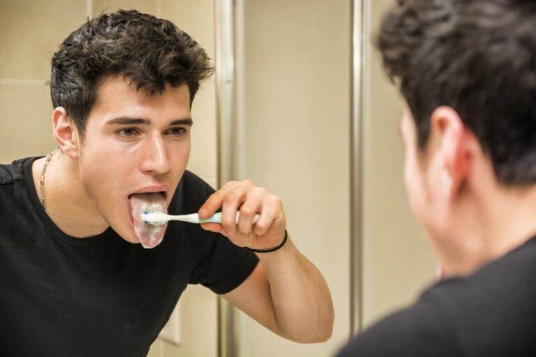 Young man brushing his tongue