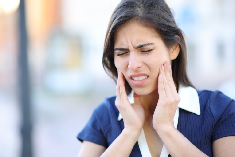 Young woman experiences jaw pain due to stress-induced teeth grinding and clenching