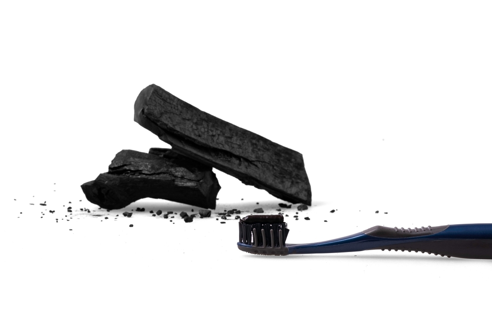 Activated charcoal natural whitening toothpaste displayed next to a broken piece of charcoal, portraying the idea that charcoal toothpaste is harsh and too abrasive