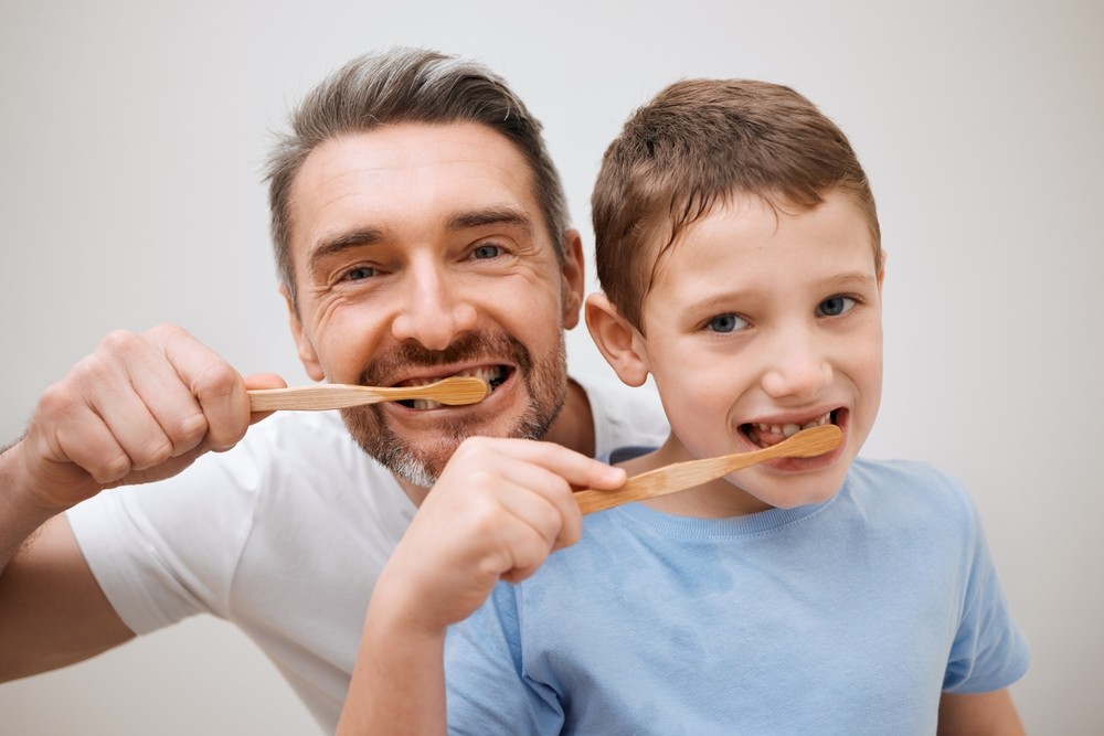 Dad & son brush teeth together with toothpaste containing hydroxyapatite