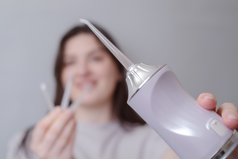 Blurred image of teen with braces holding a water flosser