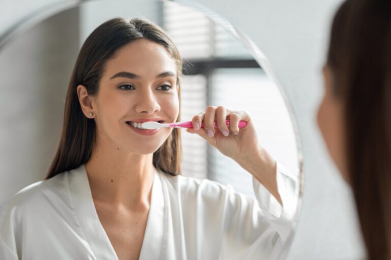 Teenage girl brushes teeth with pink toothbrush